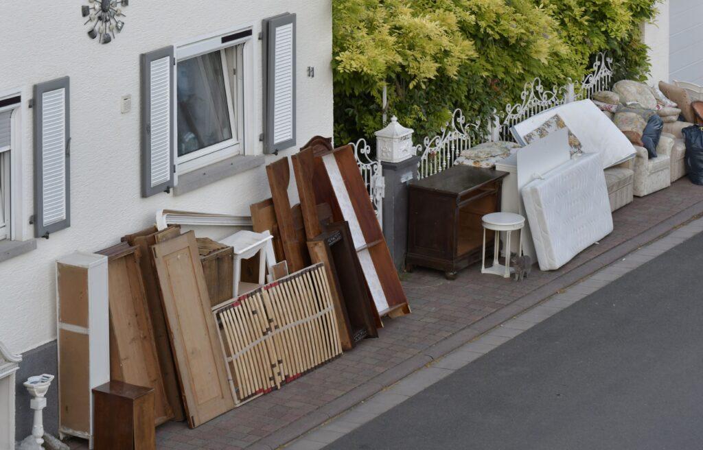 Alte Möbel und Matratzen stehen ordentlich gestapelt am Gehweg vor einem Haus, bereit zur Abholung als Teil einer Haushaltsauflösung in Mönchengladbach.