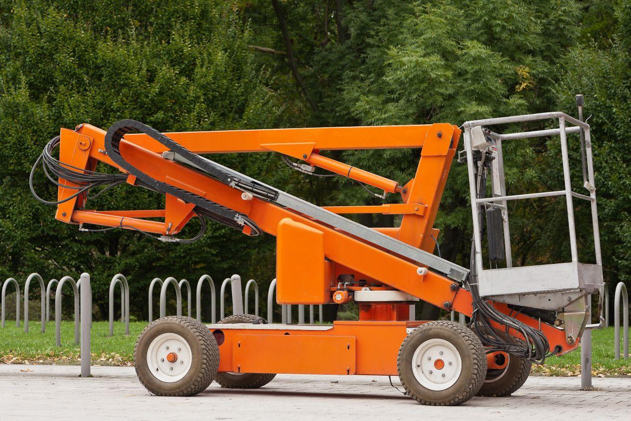 Orangefarbene Gelenk Teleskop Arbeitsbühne im eingeklappten Zustand – ideal für enge Baustellen und flexible Höhenarbeiten im Außenbereich