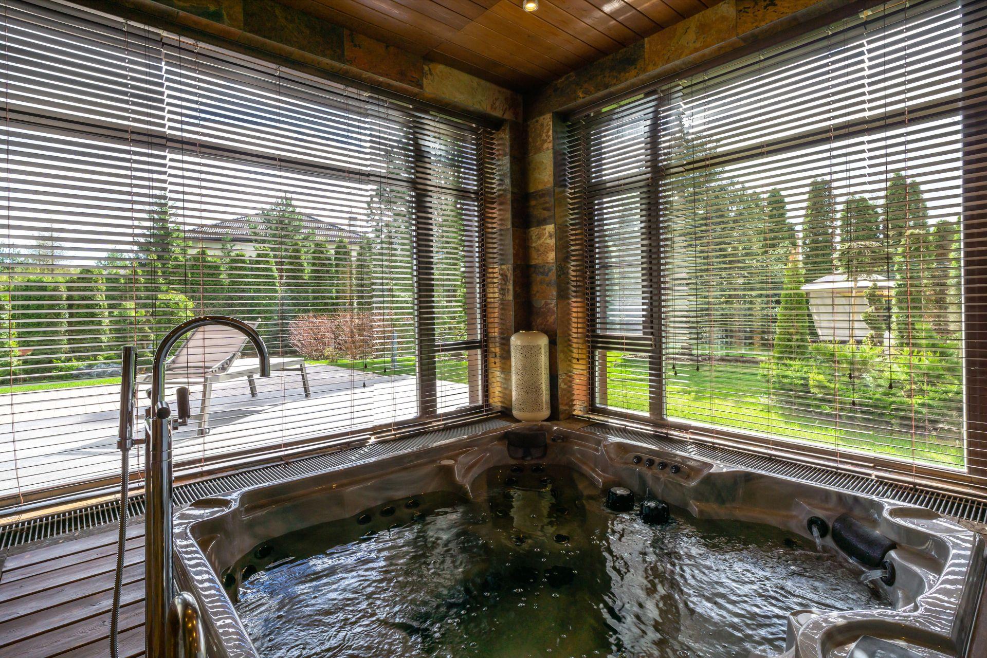 Indoor Whirlpool mit Blick in den Garten fuer Wohlfuehlatmosphaere und Wellness zu Hause