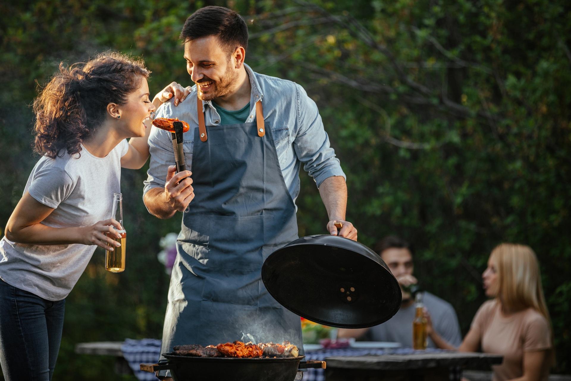 Paar lacht beim Grillen in der Natur | Schwenkgrill kaufen